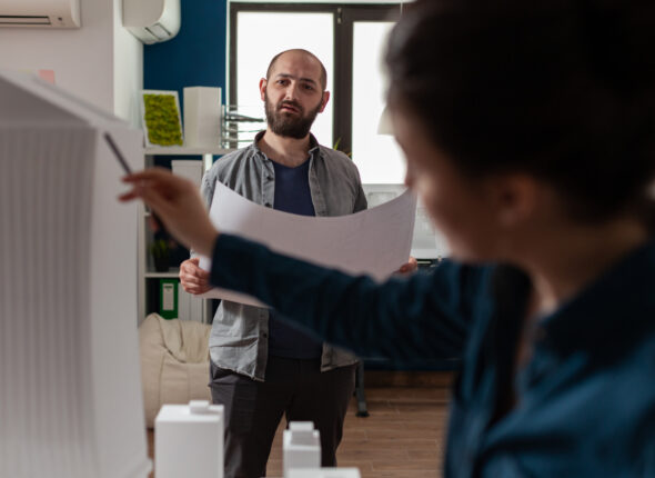 Architecture workers checking blueprints with maquette